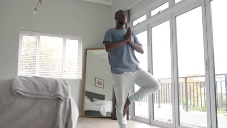 African-american-man-doing-yoga-and-meditating-at-home,-slow-motion