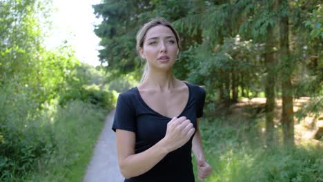 blonde woman in a black top and gray exercise pants jogging in a park