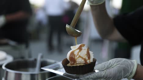 el sirviente llena de jarabe de caramelo caliente en el postre de helado de vainilla.