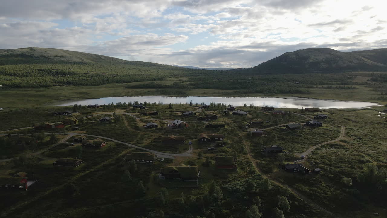 toma aérea de casas en el valle verde con lago y montaña en el fondo venabygd, noruega