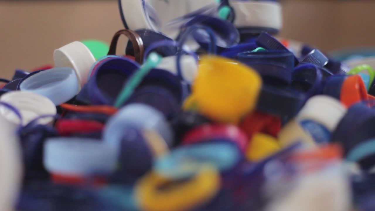 manos apilando tapas de botellas de hdpe de plástico en otra pila