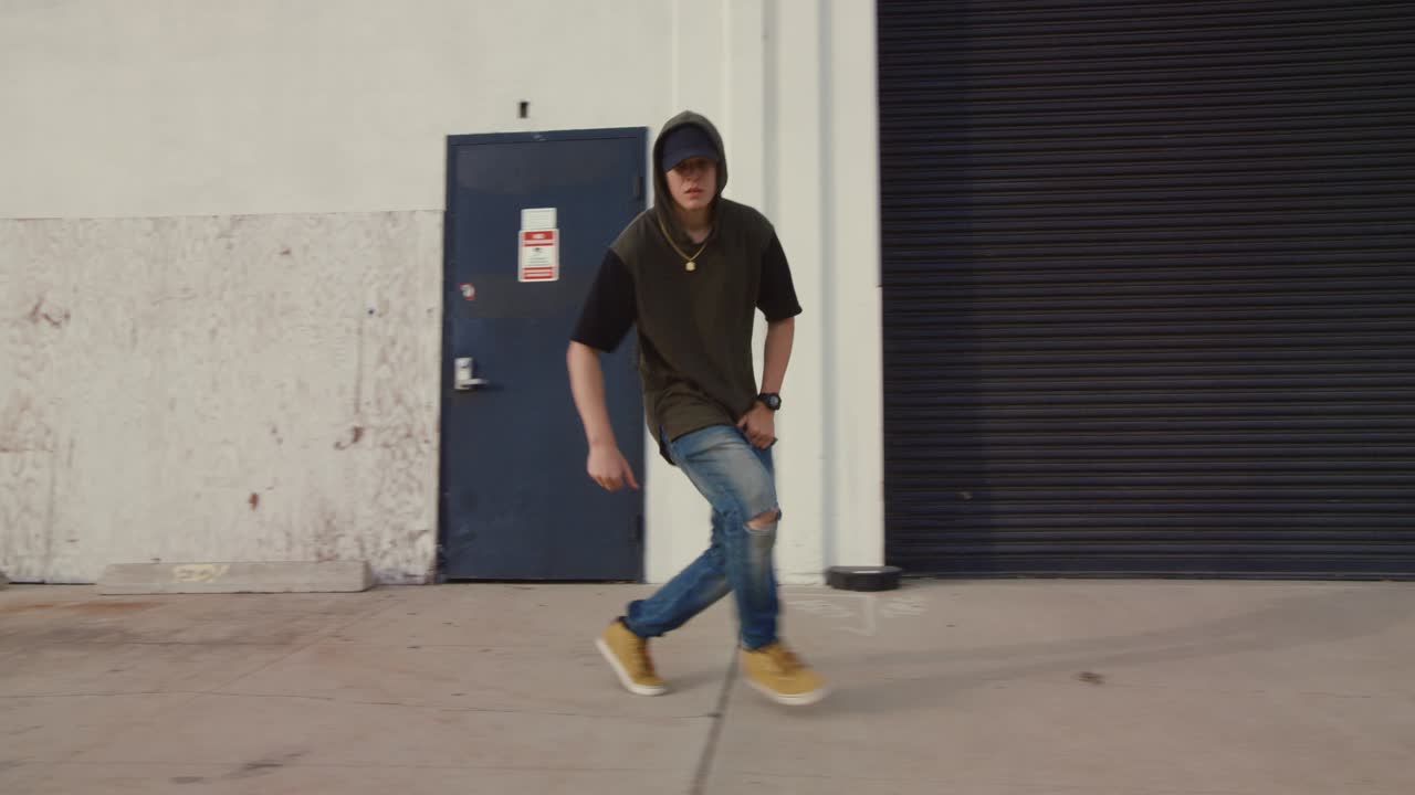 Uomo che balla hip hop freestyle lungo il marciapiede cittadino