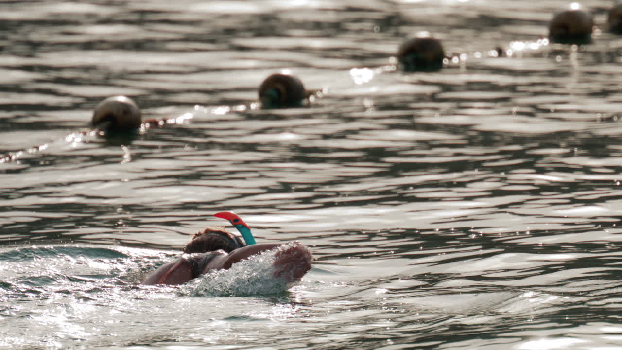 A woman snorkeling in the ocean, floating in gentle water under soft sunlight