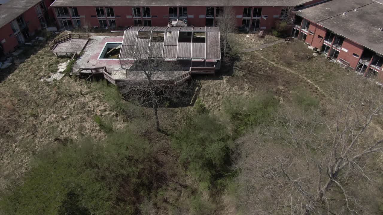 공중 드론 영상이 늦겨울 동안 버려진 호텔을 향해 앞으로 돌리고 아래로 패닝합니다.