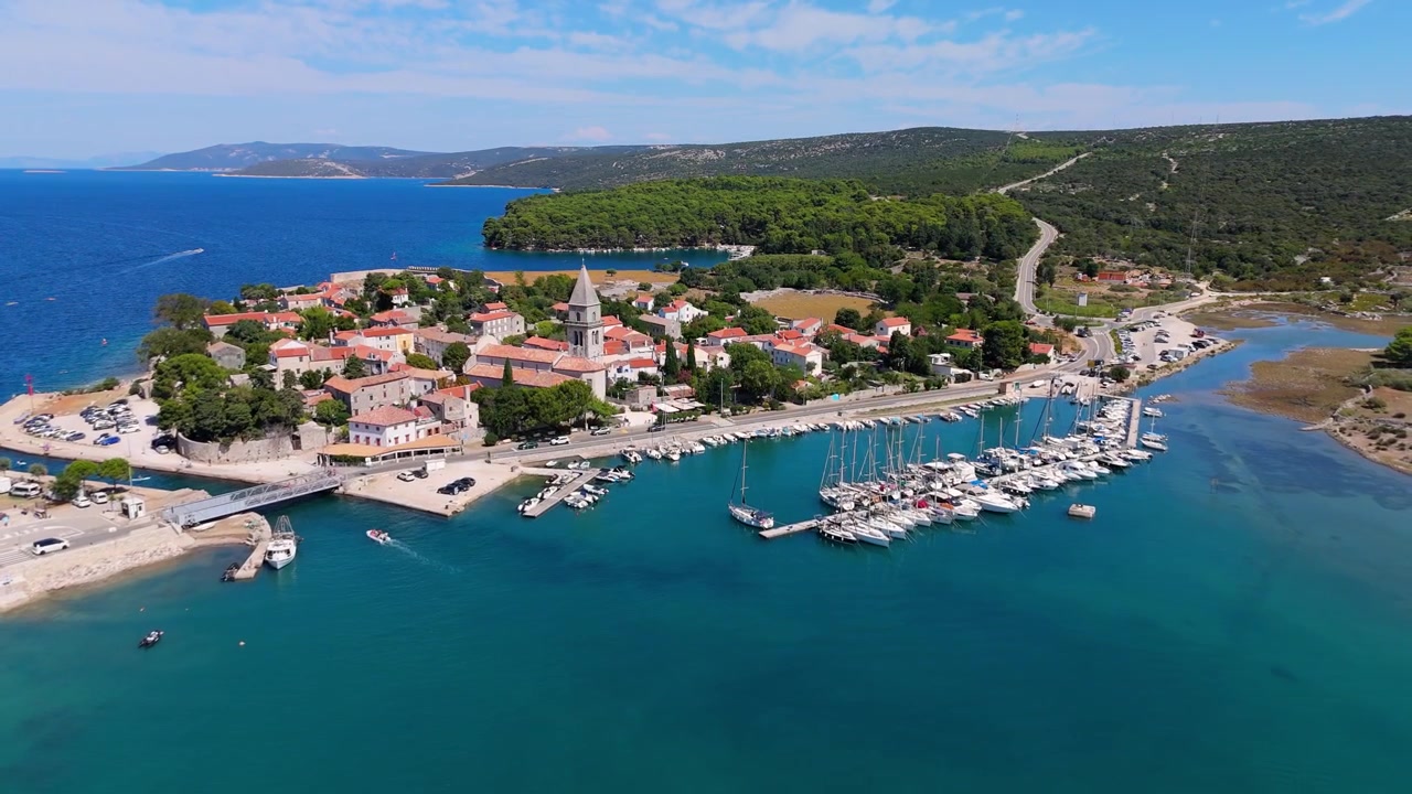Panorama della città di Osor sull'isola di Cherso, Croazia, in una splendida giornata estiva. Le viste aeree mostrano il centro storico, spiagge soleggiate, yacht a vela, il porto turistico e campeggi vicini sulla costa adriatica mediterranea
