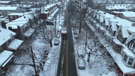 Bus-stopping-at-station-of-snowy-street-in-american-neighborhood