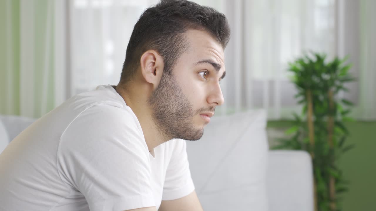 우울한 생각의 젊은이가 집에서 슬프고 불행합니다.