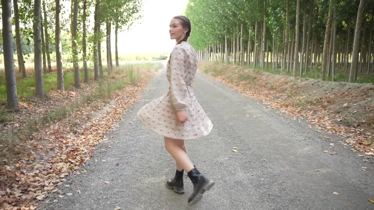 Una donna passeggia lungo un sentiero circondato da una foresta lussureggiante, abbracciando la tranquillità della natura.