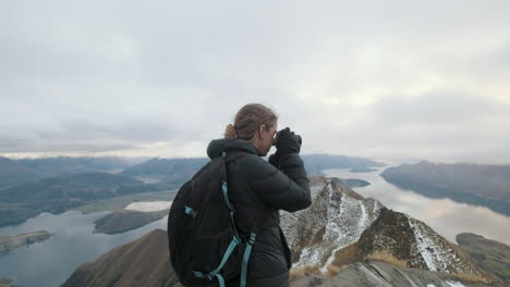 hiker taking photos at the top of roy's peak in wanaka, new zealand