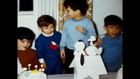 young boy blowing out candles on a cake. circa usa - 1970s: a young boy with a birthday cake blowing out the candles during a celebration in the 1970s in the usa.