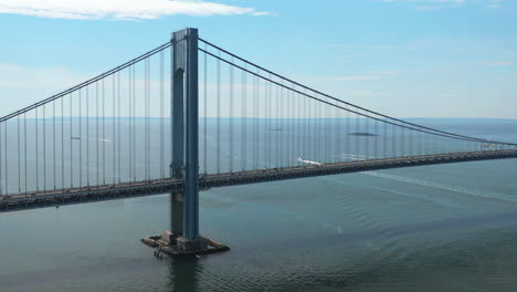 Luftaufnahme-Der-Verrazano-Brücke,-Während-Die-Kamera-Der-Drohne-Nach-Rechts-Schwenkt-Und-An-Einem-Sonnigen-Morgen-Staten-Island-Und-Das-Darunter-Liegende-Wasser-Betrachtet,-Umlaufbahn-3