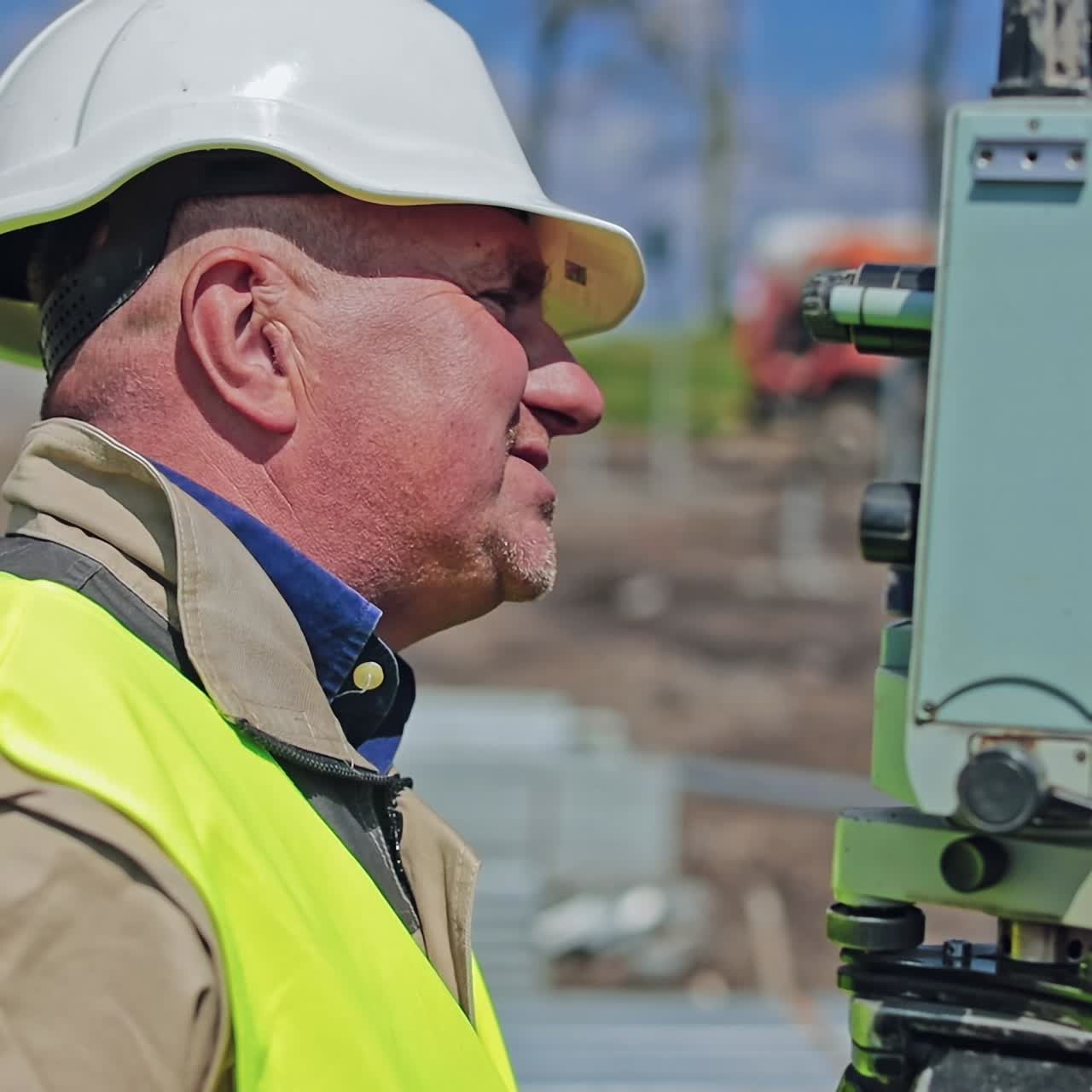 Side view portrait of a worker. Male engineer in uniform and hard hat standing on the field during the construction of solar farm. Close-up.