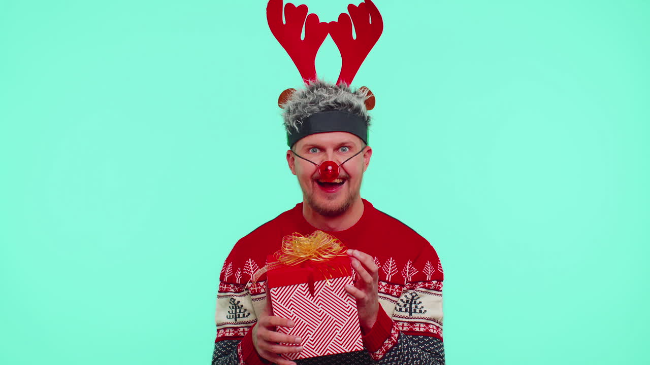 스웨터를 입은 쾌활한 남자 산타 크리스마스 모자 선물 상자, 놀라움 행복을 표현