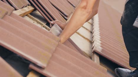 closeup of worker removing roof tiles for home solar panel installation