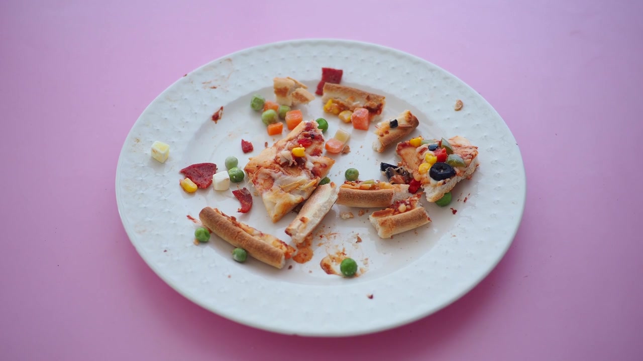 Piatto disordinato con avanzi di pizza e verdure sparse