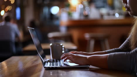 person typing on a laptop in a cafe