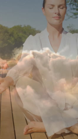 animation of clouds over caucasian couple practicing yoga and meditating