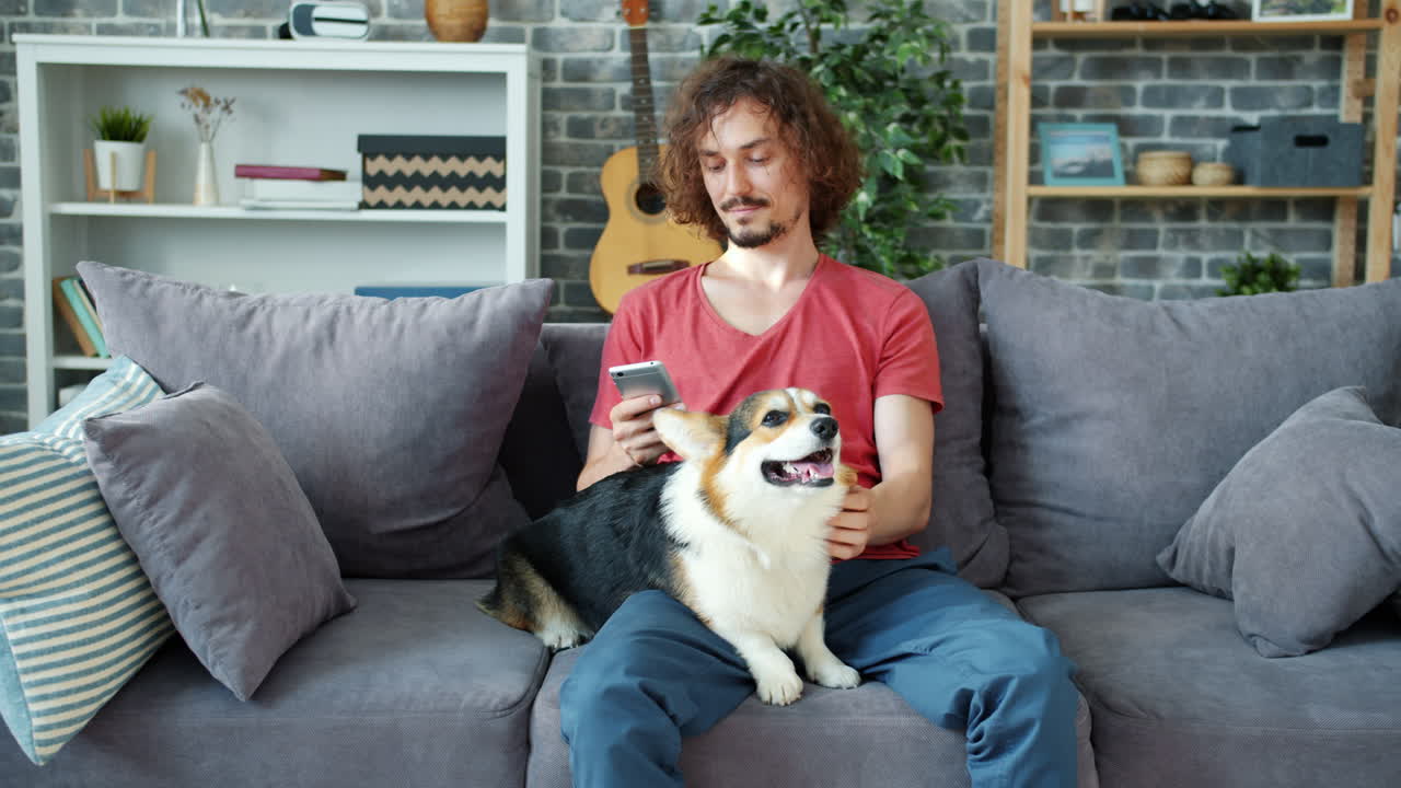 Man relaxing on couch with his corgi