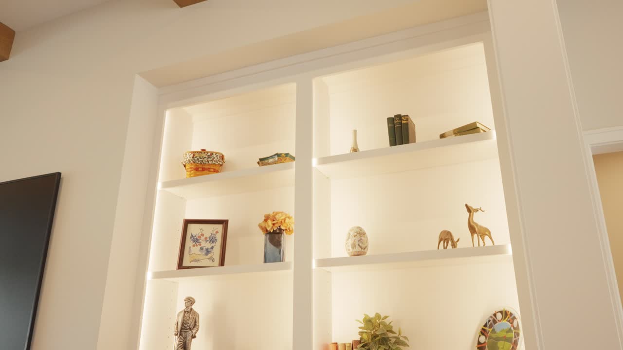 Illuminated display cabinet in modern spacious living room with decorative ornaments on the shelves