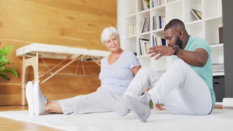 video of african american male physiotherapist exercising with caucasian senior woman