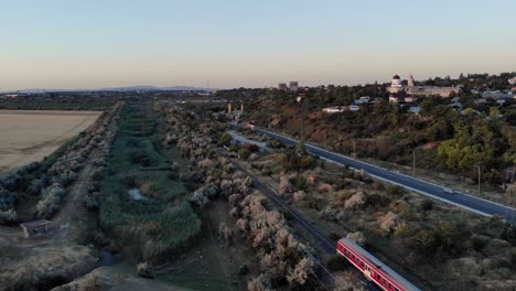 tren local rojo que viaja a lo largo de los vehículos que circulan por la carretera