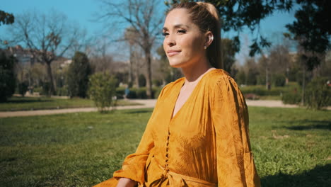 stylish young woman sitting in the grass outdoors.