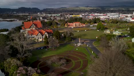 Amazing-drone-crane-rising-of-historic-Rotorua-Museum-and-Government-Gardens-city-park,-New-Zealand