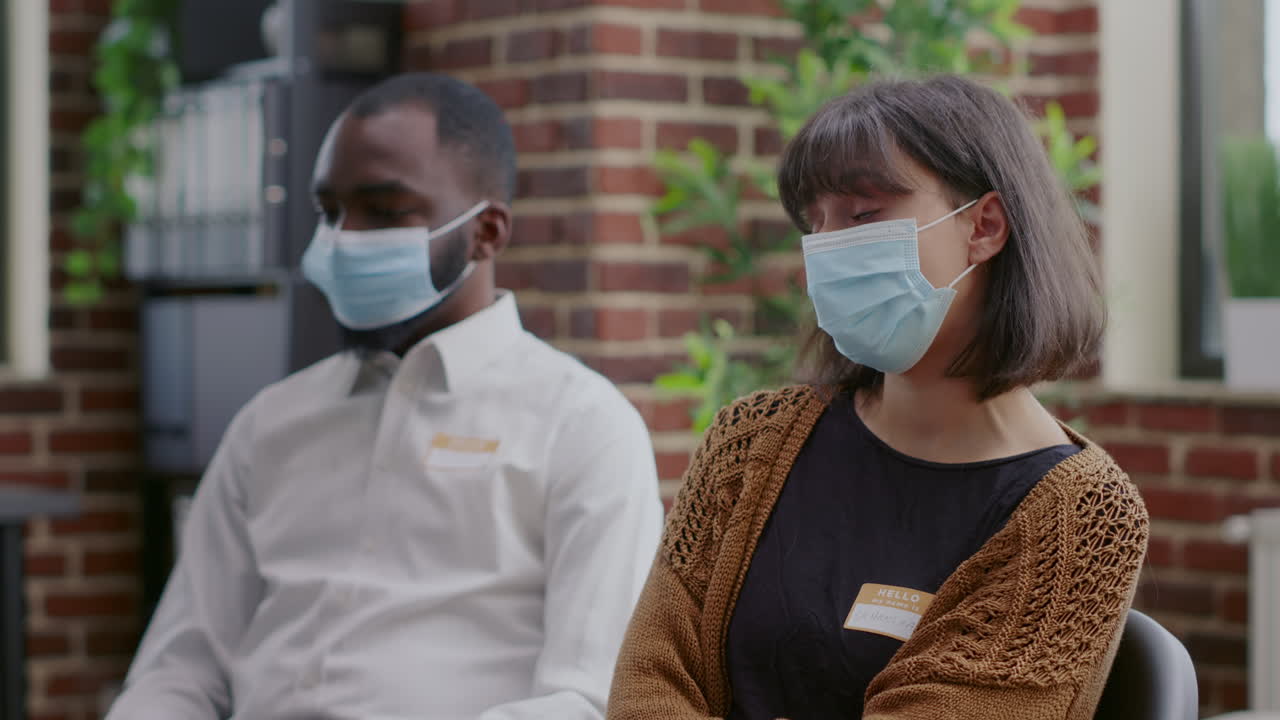 Close up of woman attending aa therapy meeting with people during covid 19 pandemic