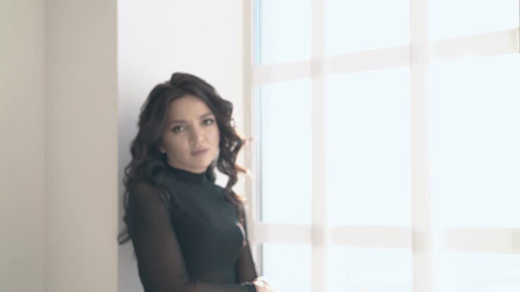 una bella ragazza arrabbiata in abiti neri viene alla finestra in soffitta.