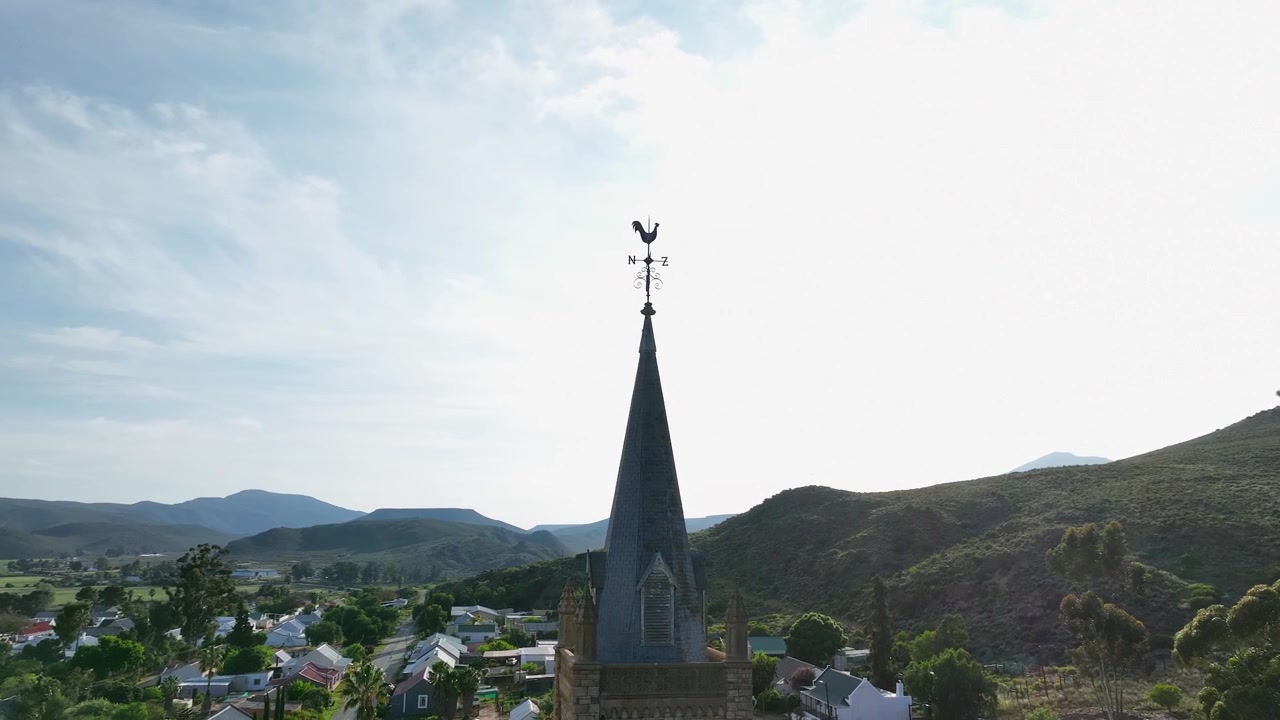 Güneşli gökyüzüne karşı kilise kulesinin tepesinde horoz rüzgar gülü pusulası.