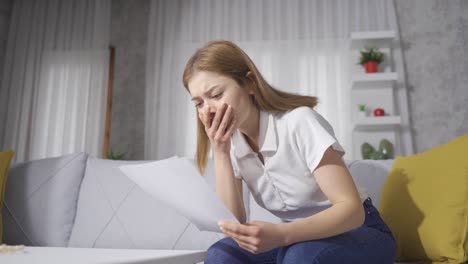 sad woman looking at papers in her hand. bad news.