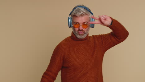 hombre mayor feliz con auriculares escuchando música bailando discoteca divirtiéndose relajándose en la fiesta de navidad