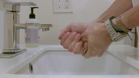 slow motion of a man washing his hands in a bathroom sink.