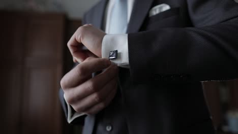 handsome groom man fixes his cuffs on a jacket with cufflinks. businessman