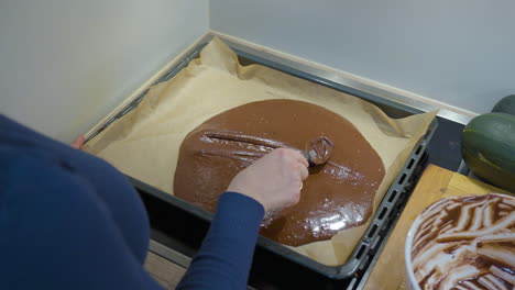 woman filling baking tray with chocolate brownie dough in slow motion