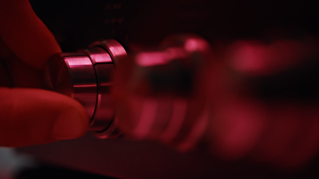 Fingers rotating volume knob at dark room closeup. Macro man adjusting sound