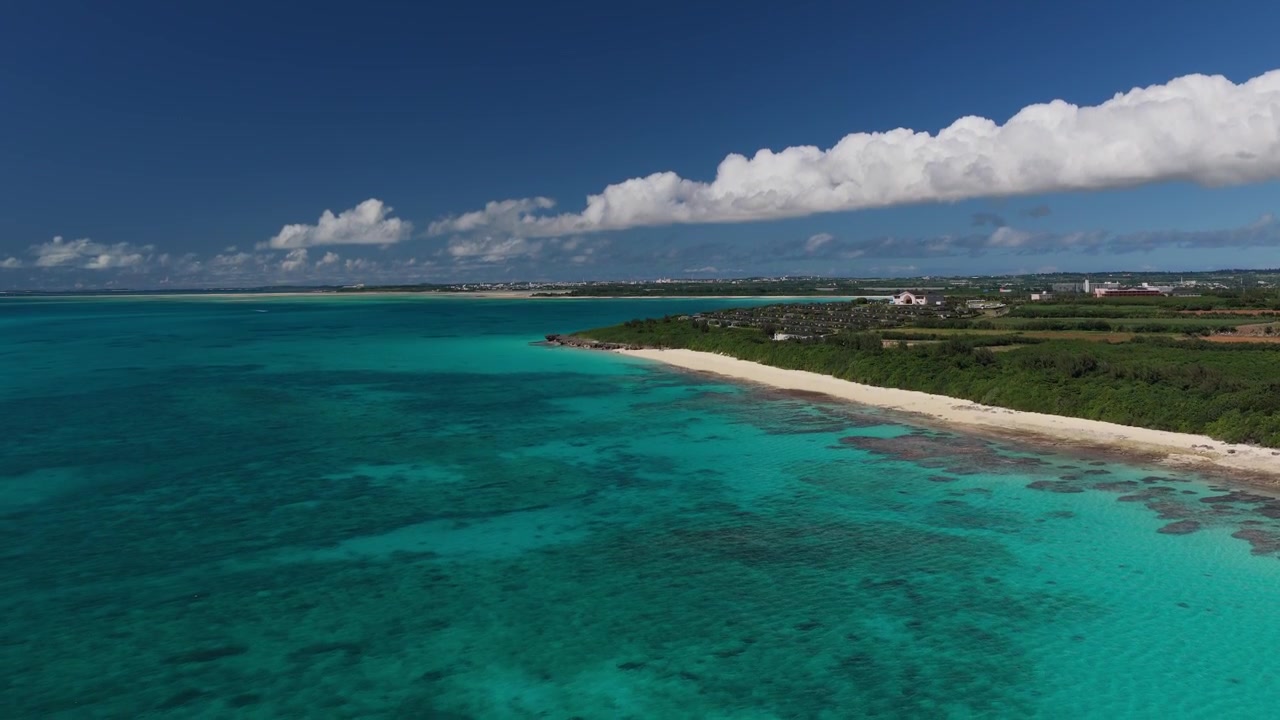 Inquadratura orizzontale in cameo con carrellata all'indietro in ascesa da un'angolazione obliqua elevata sopra la spiaggia di Musunun e le sue acque costiere turchesi