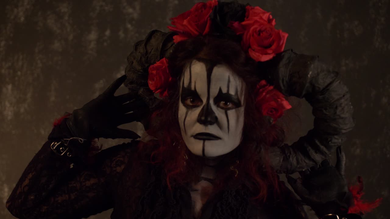 Catrina Cosplay meisje beweegt haar handen langzaam boven haar hoofd tegen een donkere achtergrond, medium close-up