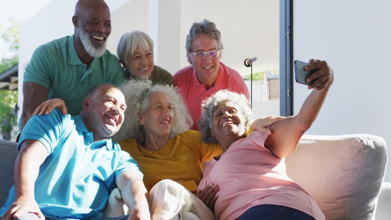 Glückliche ältere, diverse Menschen machen ein Selfie in einem Seniorenheim.