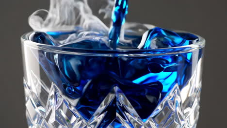 pouring vibrant blue drink into a crystal glass