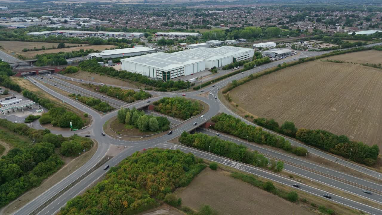 Aerial drone view of Bedford England motorway highway junction roundabout with heavy traffic, industrial warehouses and retail park commercial landscape