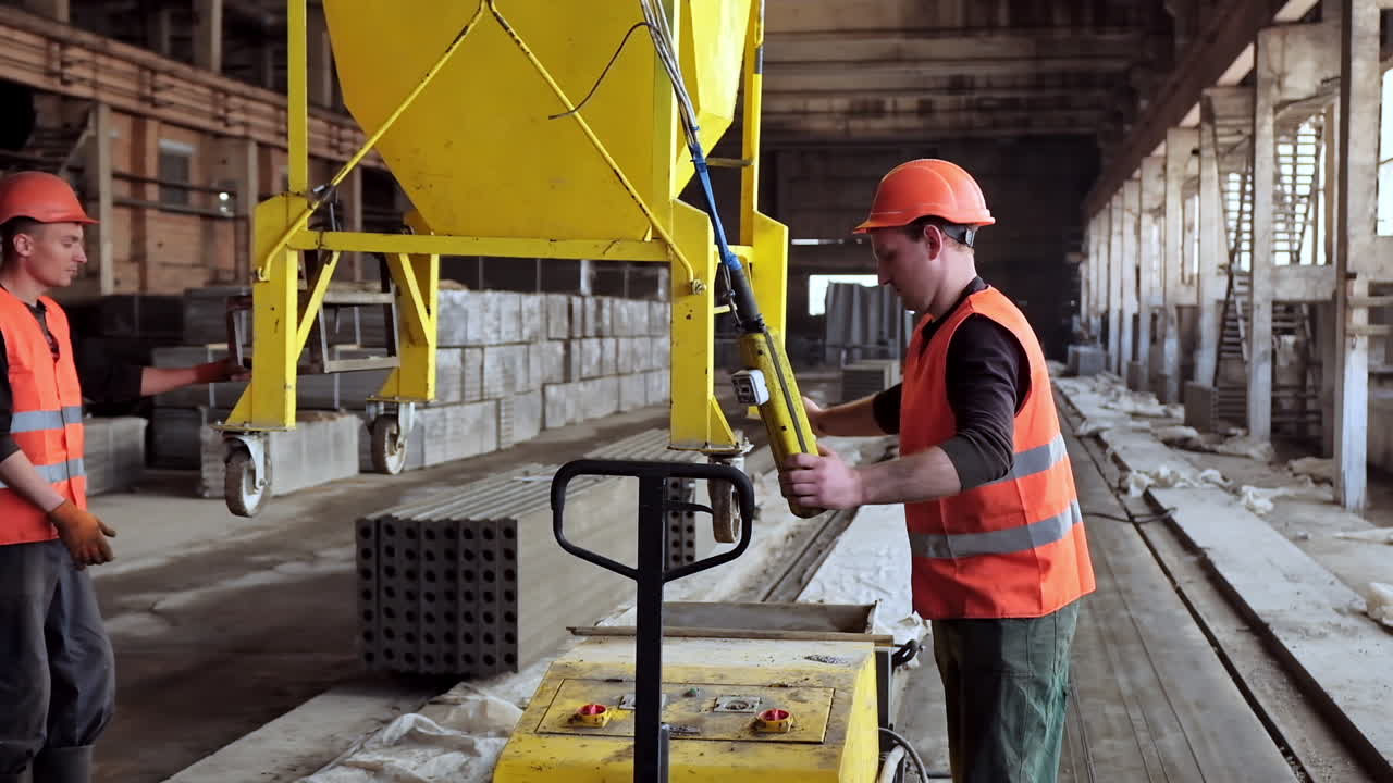 Workers on the concrete plant. Plant for the creation of reinforced concrete slabs. Employees in hard hat work inside manufacturing. Heavy industry concept.
