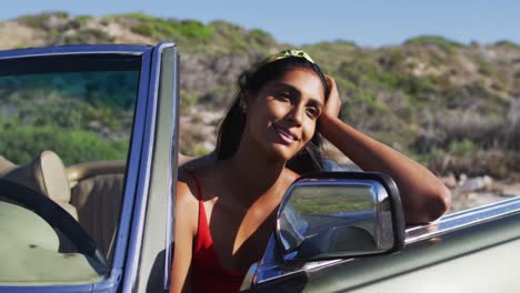 mujer afroamericana con gafas de sol sentada en el coche descapotable en la carretera