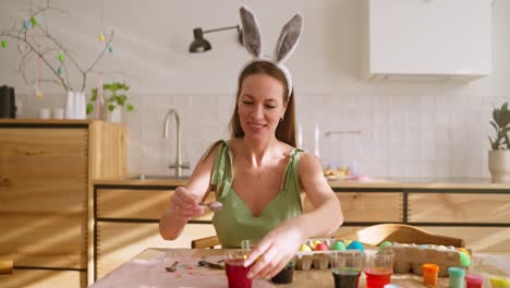 Woman decorating Easter eggs in her kitchen