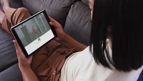 compuesto de una mujer en el sofá en casa viendo atletismo corriendo evento en la tableta