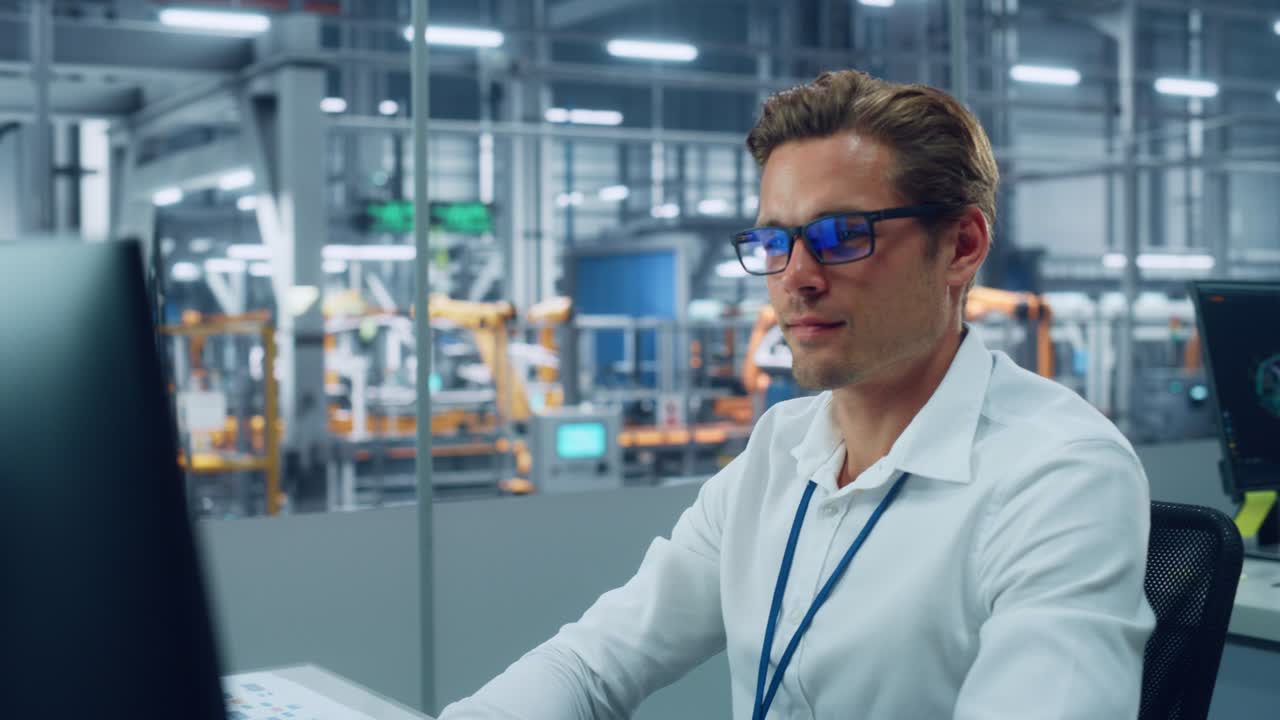 Professional Automotive Engineer Working on Desktop Computer in Modern Office at Car Assembly Plant. Industrial Project Manager Organizing Sales, Finance and Marketing Reports at Vehicle Factory.