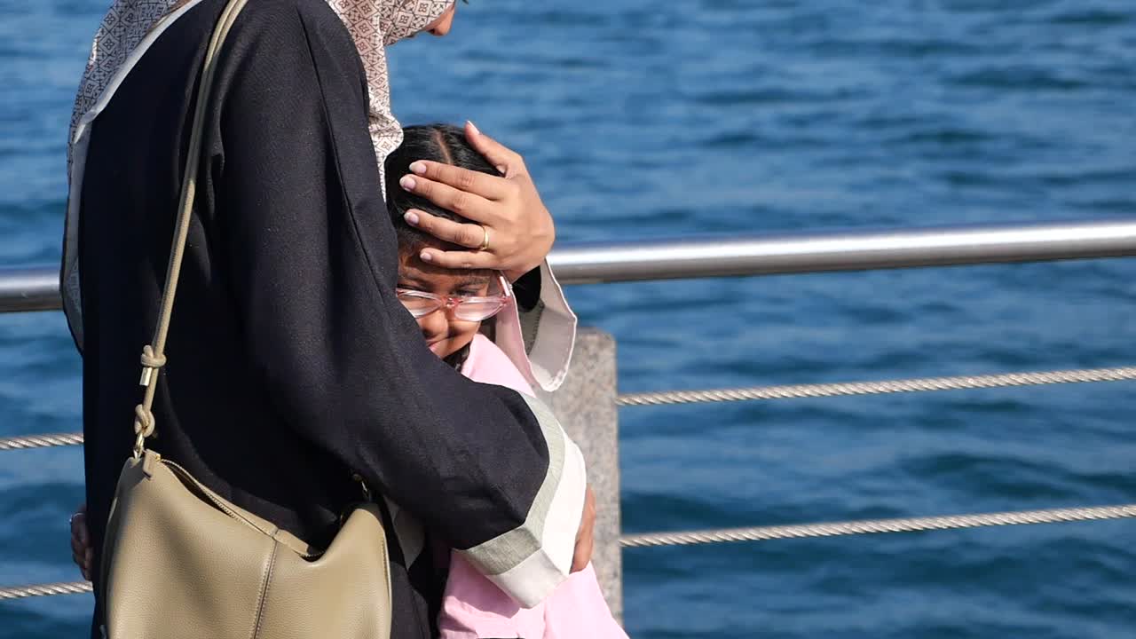 A mother and child embrace by the sea