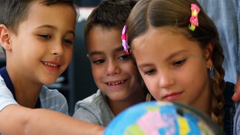 niños de la escuela discutiendo sobre el globo en el aula