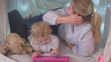 Madre-E-Hija-Pequeña-Con-Tableta-Digital-En-Un-Campamento-Casero-En-El-Dormitorio-De-Un-Niño-En-Casa---Filmadas-En-Cámara-Lenta