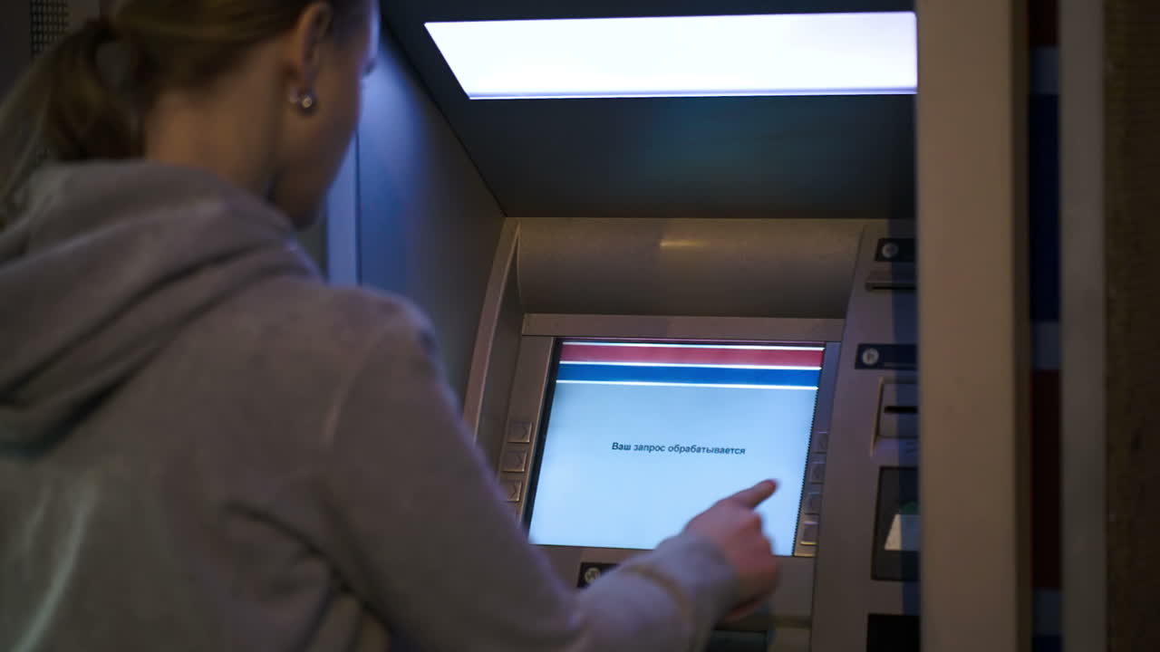 Woman using ATM outdoor in the evening